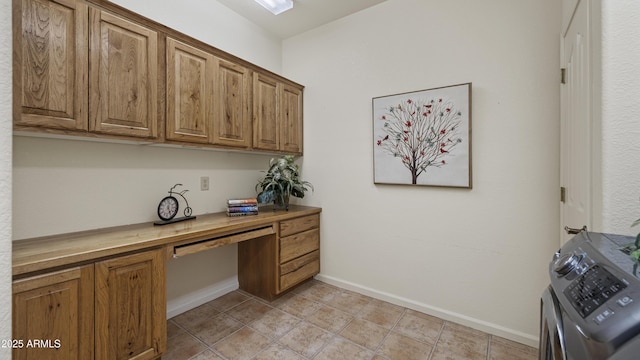 office area featuring light tile patterned floors, built in desk, washer / dryer, and baseboards