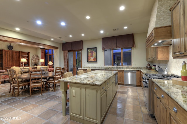 kitchen with a kitchen island, appliances with stainless steel finishes, a breakfast bar area, and light stone counters