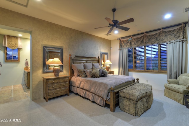 carpeted bedroom with ensuite bath and ceiling fan