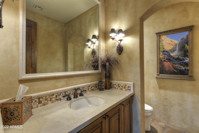 bathroom featuring vanity, backsplash, and toilet