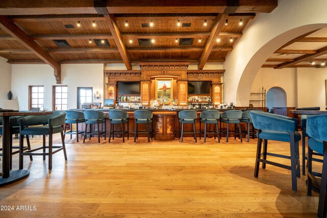 bar with beam ceiling, light hardwood / wood-style flooring, and wooden ceiling