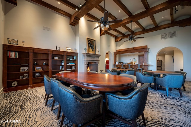 carpeted dining area featuring beamed ceiling, ceiling fan, and high vaulted ceiling