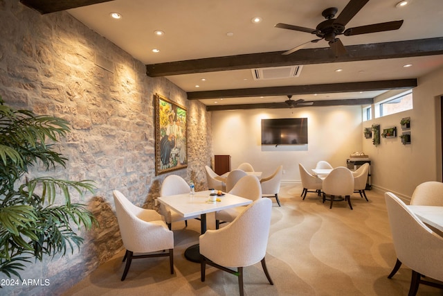 carpeted dining area with beamed ceiling and ceiling fan