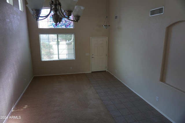 unfurnished dining area featuring tile patterned floors, a towering ceiling, and a notable chandelier