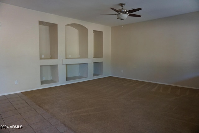 empty room with tile patterned floors, built in features, and ceiling fan