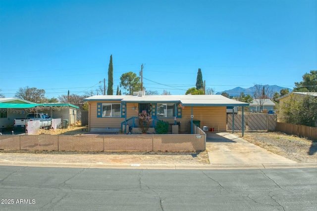 view of front of property with driveway, an attached carport, a fenced front yard, and a mountain view