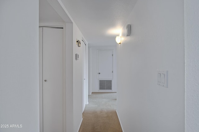 hallway with light carpet and a textured ceiling