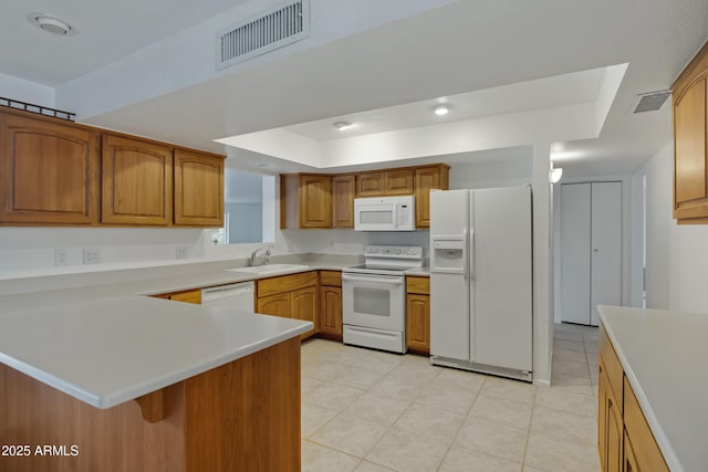 kitchen with sink, white appliances, a tray ceiling, and kitchen peninsula