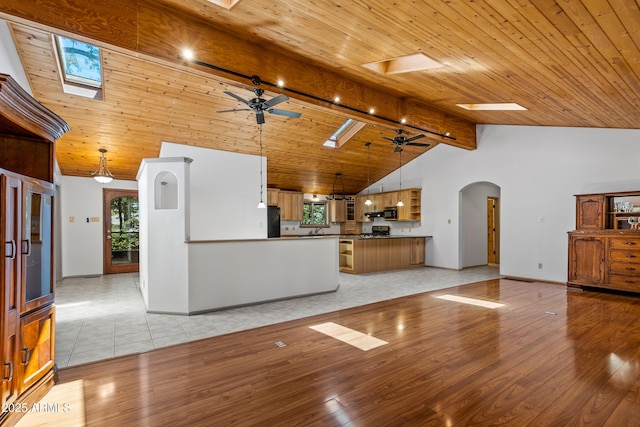 17620 Littlefield Pl, Munds Park, AZ 86017 - unfurnished living room with ceiling fan, arched walkways, a skylight, a wooden ceiling with exposed beams, and light wood-style floors