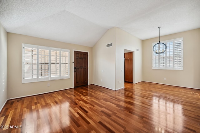 unfurnished room with lofted ceiling, a textured ceiling, wood-type flooring, and a chandelier