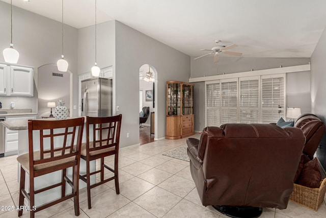 living area with light tile patterned floors, visible vents, high vaulted ceiling, and a ceiling fan