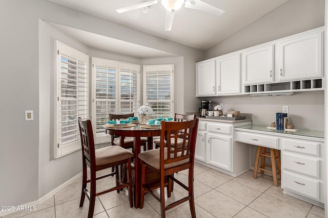 dining space featuring light tile patterned flooring, built in desk, a ceiling fan, and vaulted ceiling