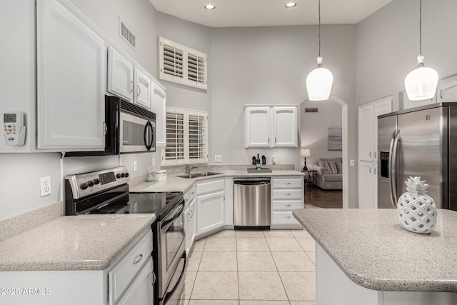 kitchen featuring visible vents, a sink, stainless steel appliances, white cabinets, and a towering ceiling