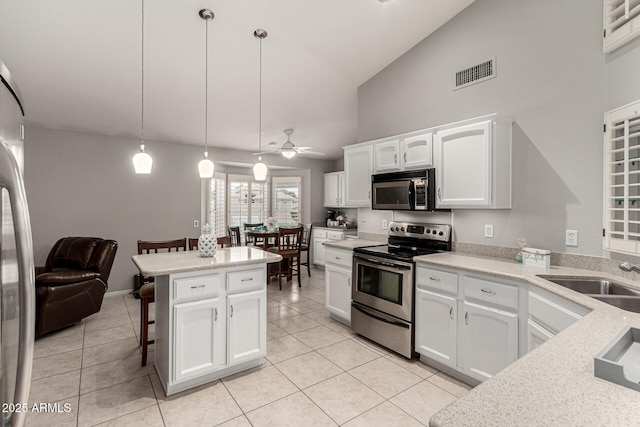 kitchen with visible vents, a sink, a kitchen breakfast bar, appliances with stainless steel finishes, and light tile patterned flooring