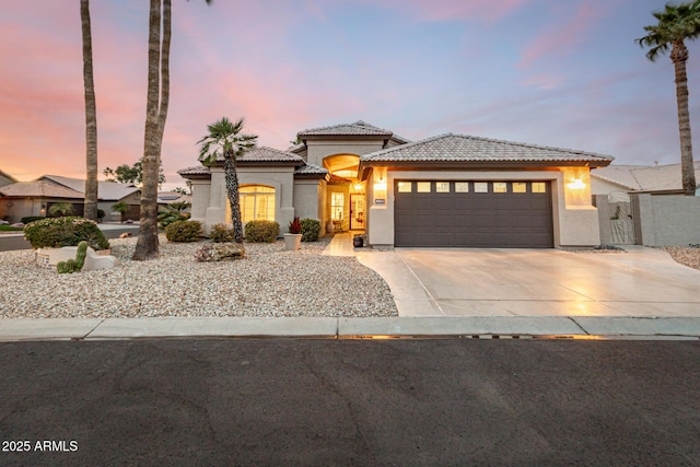 view of front of house featuring stucco siding, a garage, driveway, and a tile roof