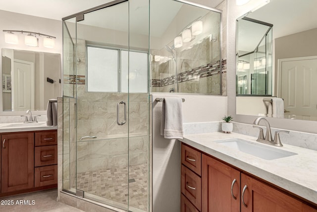 full bath featuring a shower stall, two vanities, tile patterned floors, and a sink