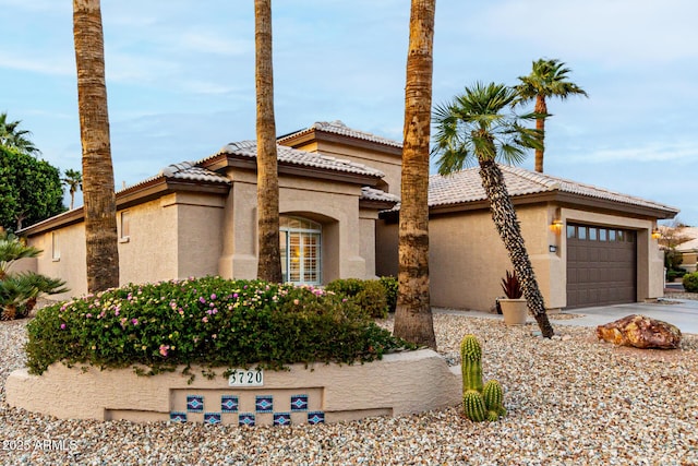 view of front of home with a tile roof, an attached garage, driveway, and stucco siding