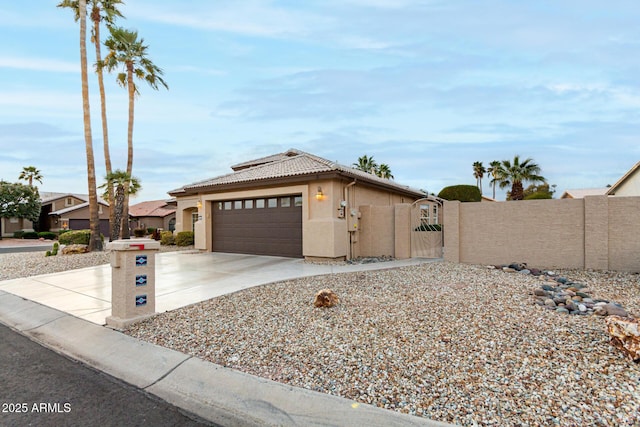 view of front facade with a tile roof, concrete driveway, stucco siding, an attached garage, and a gate