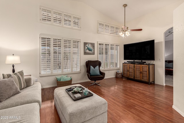 living area featuring a ceiling fan, wood finished floors, baseboards, and high vaulted ceiling