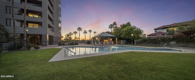 pool at dusk featuring a yard and a gazebo