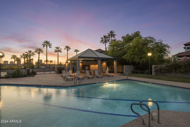 pool at dusk featuring a patio and a gazebo