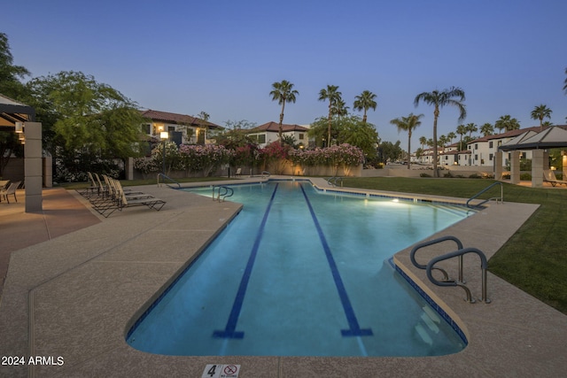 pool at dusk featuring a patio, a lawn, and a gazebo