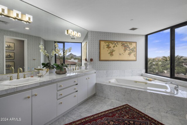 bathroom with a wealth of natural light, dual bowl vanity, tiled tub, and tile flooring