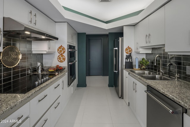 kitchen featuring white cabinets, light stone countertops, backsplash, stainless steel appliances, and sink