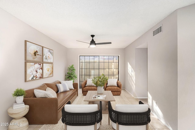 living room featuring ceiling fan and a textured ceiling