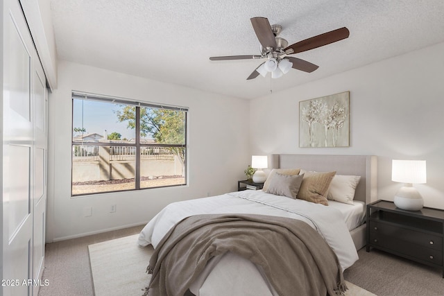 carpeted bedroom with ceiling fan and a textured ceiling