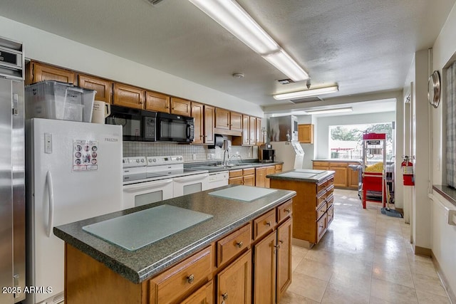 kitchen featuring sink, a textured ceiling, a kitchen island, white appliances, and decorative backsplash