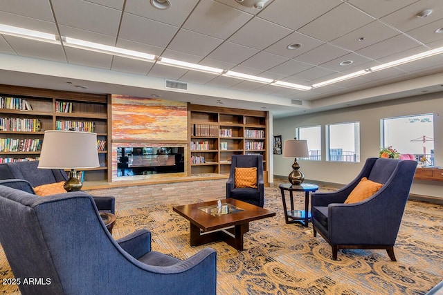 living room featuring a drop ceiling and built in shelves