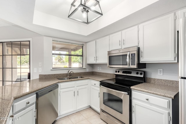 kitchen with sink, white cabinets, light tile patterned floors, a tray ceiling, and stainless steel appliances