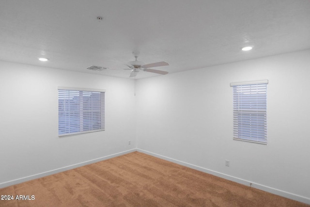 carpeted empty room with ceiling fan and a wealth of natural light