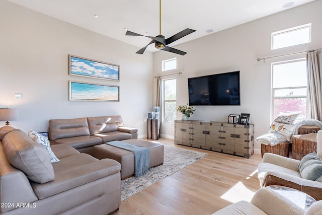 living room with a high ceiling, light hardwood / wood-style floors, and ceiling fan