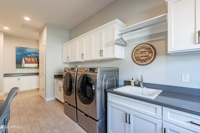 washroom with washing machine and clothes dryer, sink, cabinets, and light hardwood / wood-style flooring