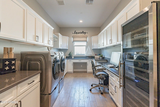 clothes washing area featuring separate washer and dryer and light hardwood / wood-style floors