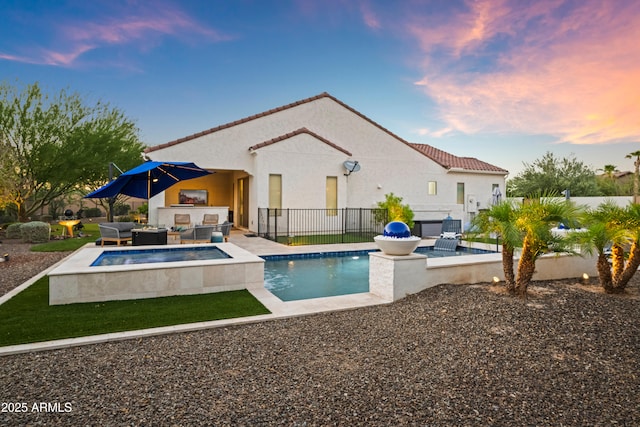 16987 W Princeton Ave, Goodyear, AZ 85395 - pool at dusk with an outdoor living space, exterior kitchen, a patio area, and an in-ground hot tub