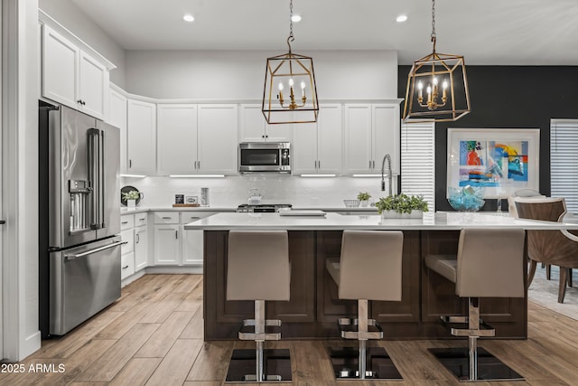 16987 W Princeton Ave, Goodyear, AZ 85395 - kitchen featuring stainless steel appliances, a chandelier, light countertops, backsplash, and an island with sink