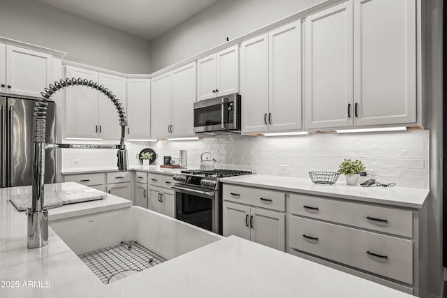 16987 W Princeton Ave, Goodyear, AZ 85395 - kitchen featuring high end appliances, decorative backsplash, white cabinetry, and light stone counters