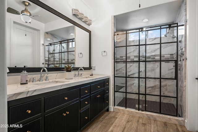 16987 W Princeton Ave, Goodyear, AZ 85395 - full bathroom with double vanity, a shower stall, wood finished floors, and a ceiling fan
