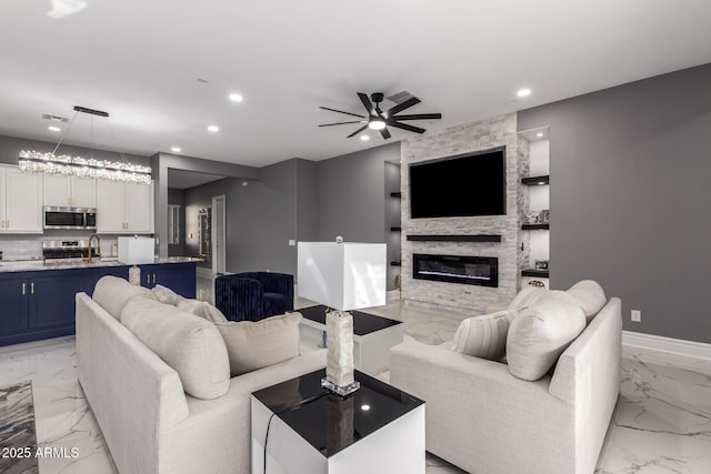 living room with ceiling fan, sink, and a fireplace