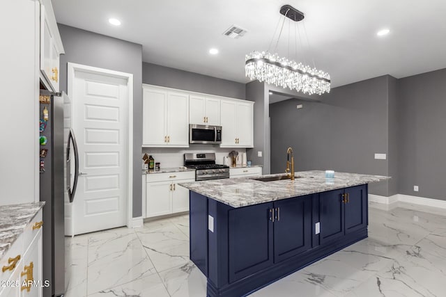 kitchen with sink, stainless steel appliances, light stone countertops, white cabinets, and a center island with sink