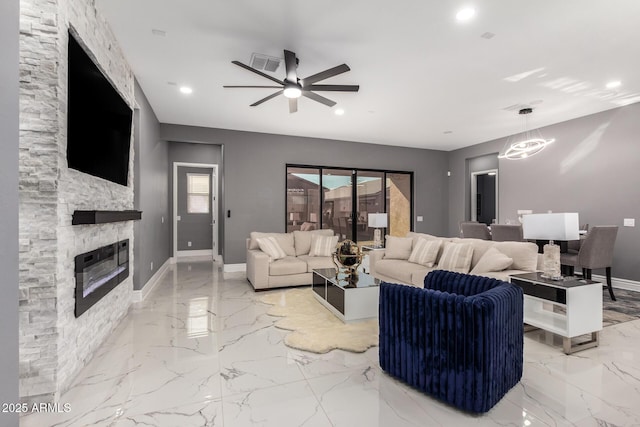 living room featuring ceiling fan and a fireplace