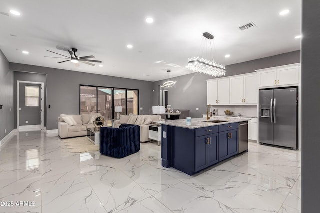 kitchen featuring appliances with stainless steel finishes, blue cabinets, sink, white cabinets, and a center island with sink