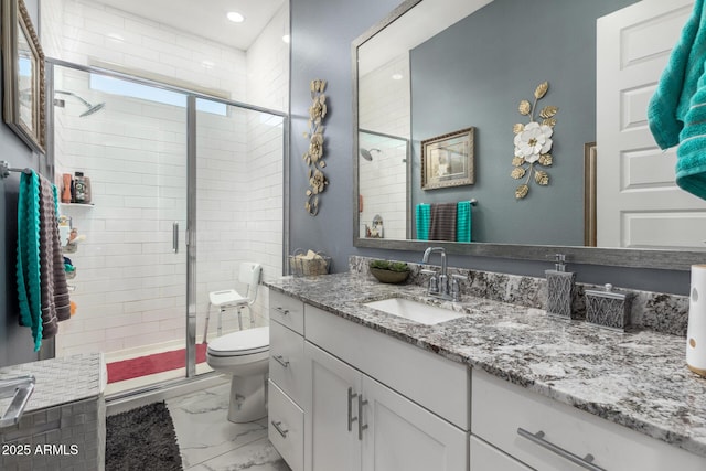 bathroom featuring a shower with door, vanity, and toilet