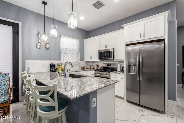 kitchen featuring sink, appliances with stainless steel finishes, pendant lighting, decorative backsplash, and white cabinets