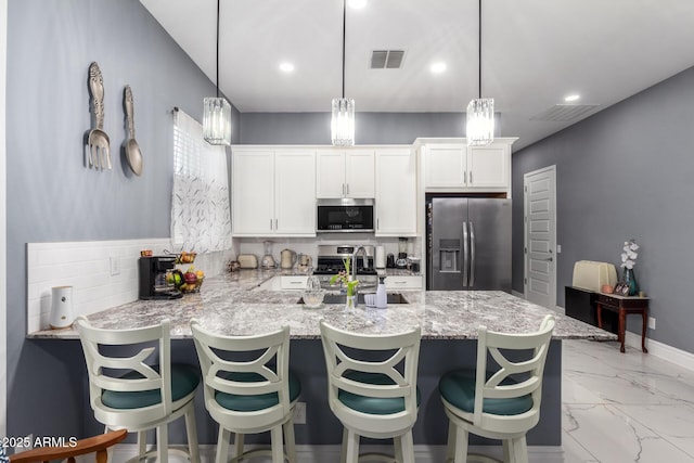 kitchen featuring pendant lighting, white cabinetry, stainless steel appliances, and kitchen peninsula