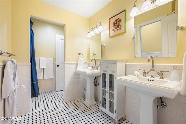 bathroom with tile patterned floors, dual sinks, and tile walls