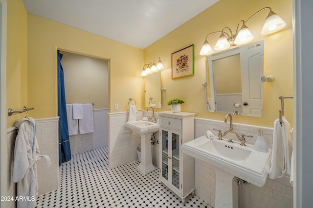 bathroom featuring tile patterned flooring, tile walls, and double sink